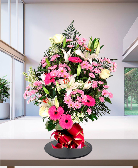 Mazzo funebre di gigli e gerbere rosa con fiocco alla base, composizione verticale