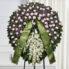 Corona funebre di colore rosa lilla e bianco montata su cavalletto, omaggio floreale a Bologna