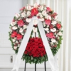 Corona funebre di fiori bianchi e rossi montata su cavalletto, omaggio floreale a Bologna