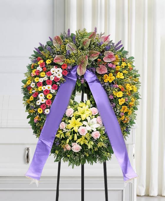 Corona funebre con fiori di stagione montata su cavalletto, omaggio floreale a Bologna
