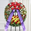 Corona funebre con fiori dai toni caldi con nastro, composizione per un funerale a Bologna