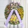 Corona funebre a settori con girasoli, gerbere e anthurium, montata sul cavalletto
