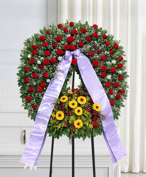 Corona funebre di rose, lisianthus bianco e gerbera gialla con nastro, composizione per un funerale a Bologna