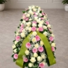 Cofano funebre di rose bianche, gerbere rosa e gisofila disteso sul feretro, omaggio floreale a Bologna
