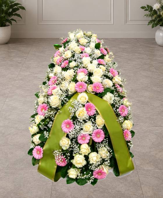 Cofano funebre di rose bianche, gerbere rosa e gisofila disteso sul feretro, omaggio floreale a Bologna
