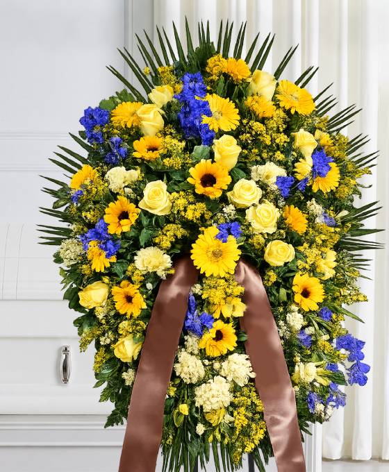 Cuscino funebre di fiori gialli e blu, composizione su sostegno per una cerimonia a Bologna