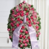 Mezzo cofano funebre di rose fucsia e gisofila, omaggio floreale accanto al feretro