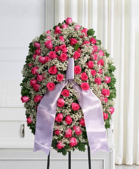 Mezzo cofano funebre di rose fucsia e gisofila, omaggio floreale accanto al feretro